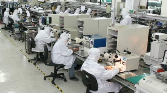 Electronics manufacturing assembly line with technicians in cleanroom suits ensuring precision and quality