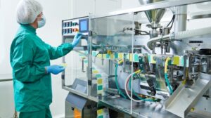 Technician operating automated packaging machine in a cleanroom environment for product manufacturing